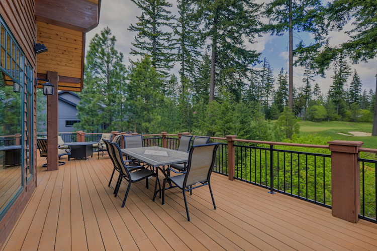 Beautiful large cabin home  with large wooden deck and chairs with table overlooking golf course.