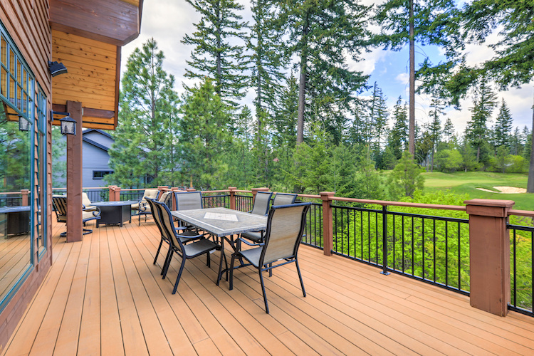 Beautiful large cabin home  with large wooden deck and chairs with table overlooking golf course.